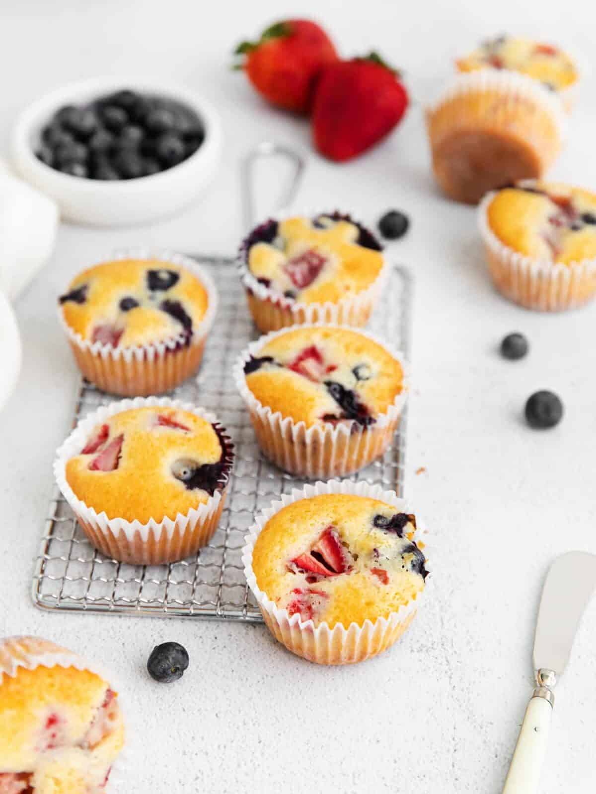 three-quarters view of 5 wildberry muffins on a small wire rack.