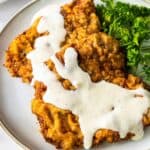 up close chicken fried steak with gravy on white plate