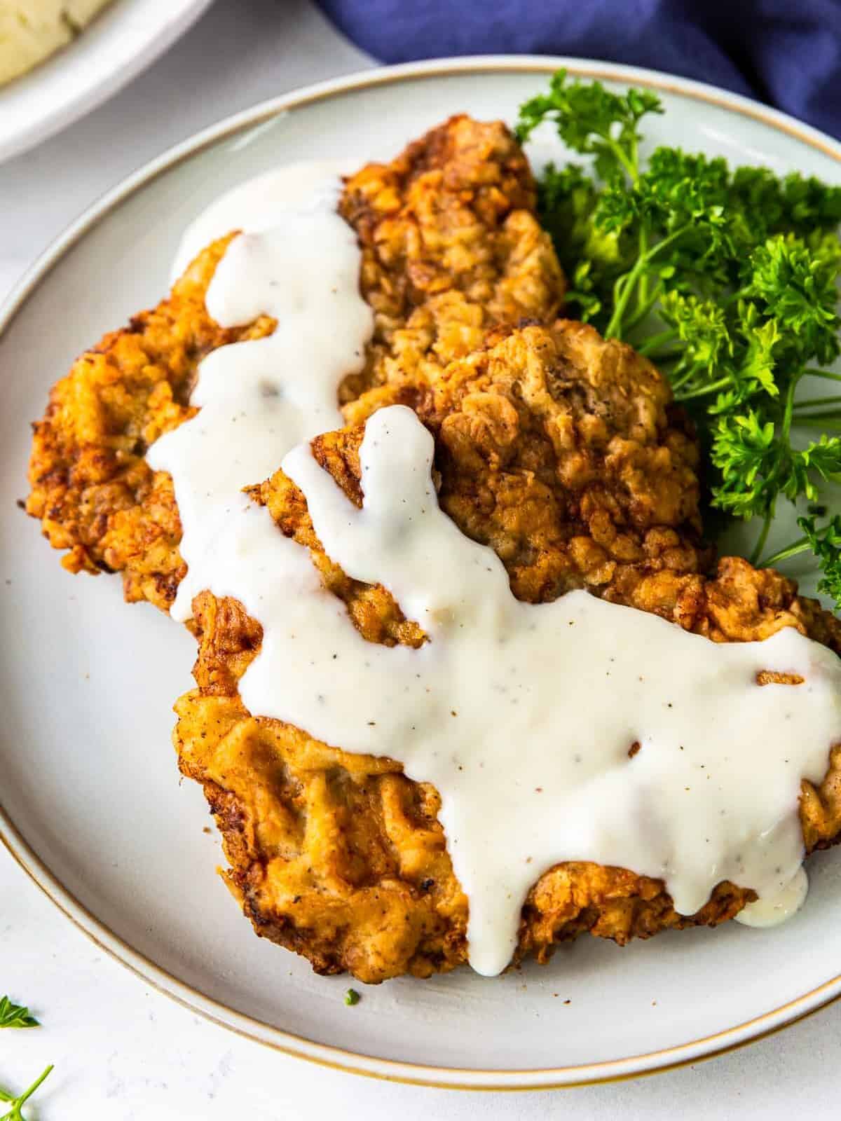 up close chicken fried steak with gravy on white plate