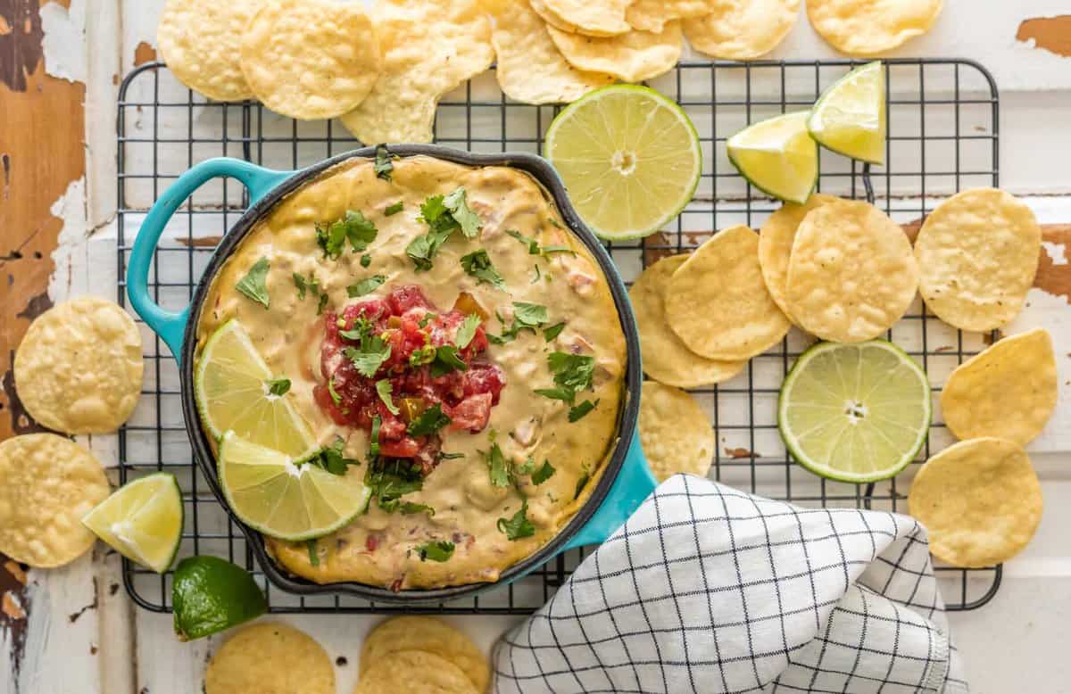 A cooling rack with a dish of dairy free queso on top, and tortilla chips scattered across it