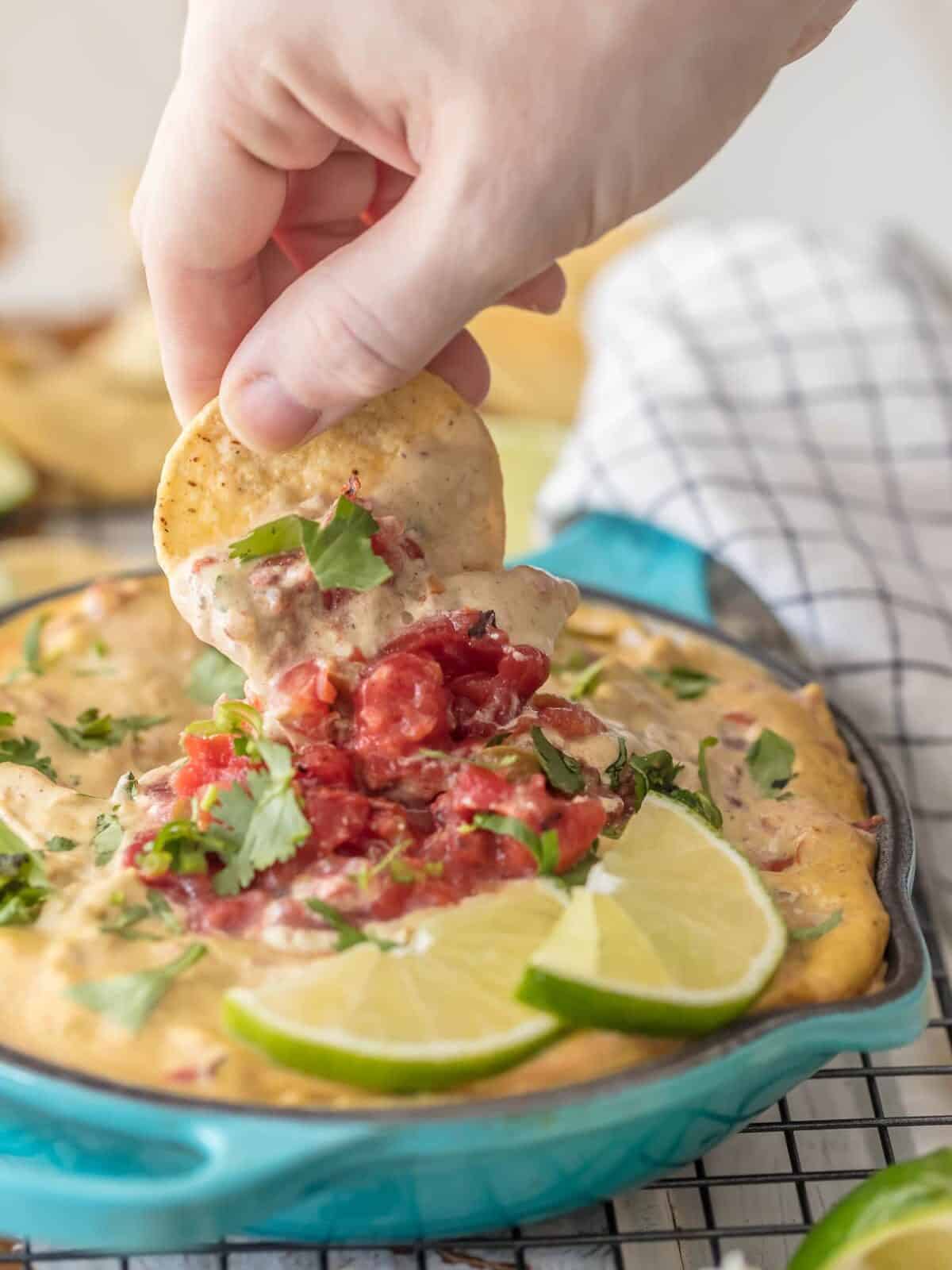 Dipping a chip into a bowl of vegan queso
