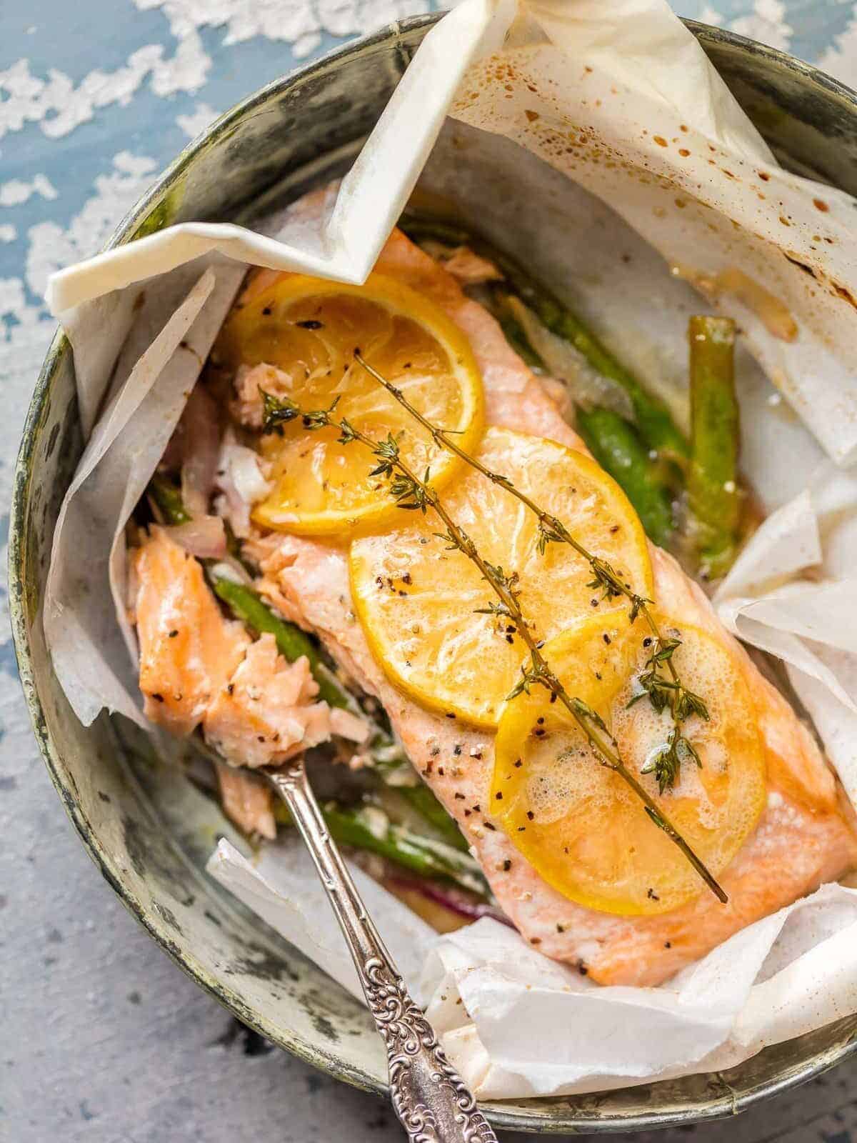 Lemon butter salmon cooked in parchment paper with asparagus.