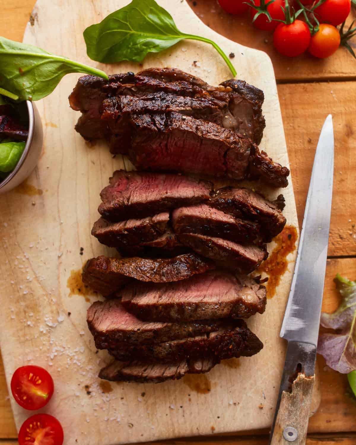 overhead view of sliced ribeye steak on a cutting board.