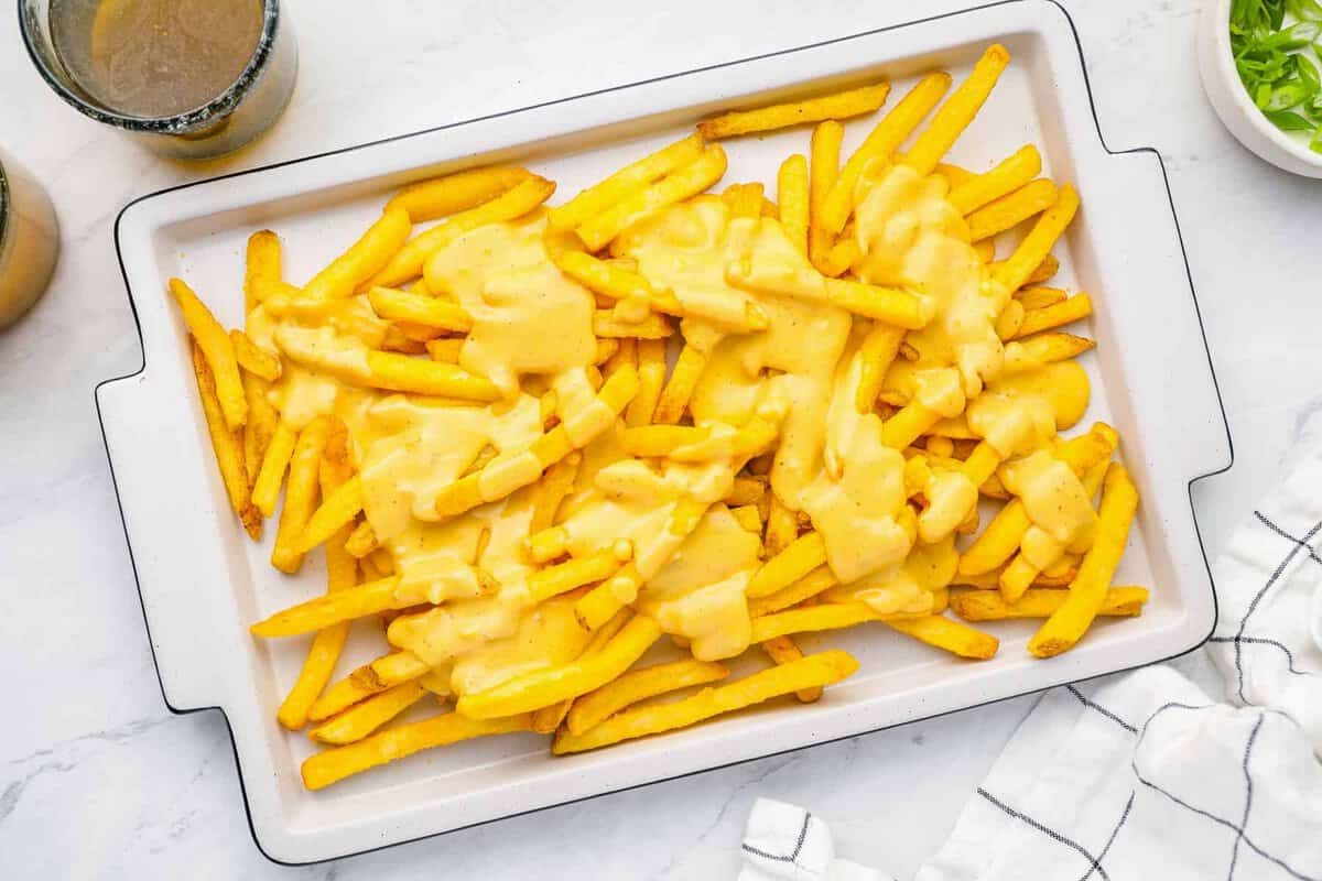 overhead view of cheese fries on a white rectangular serving dish.