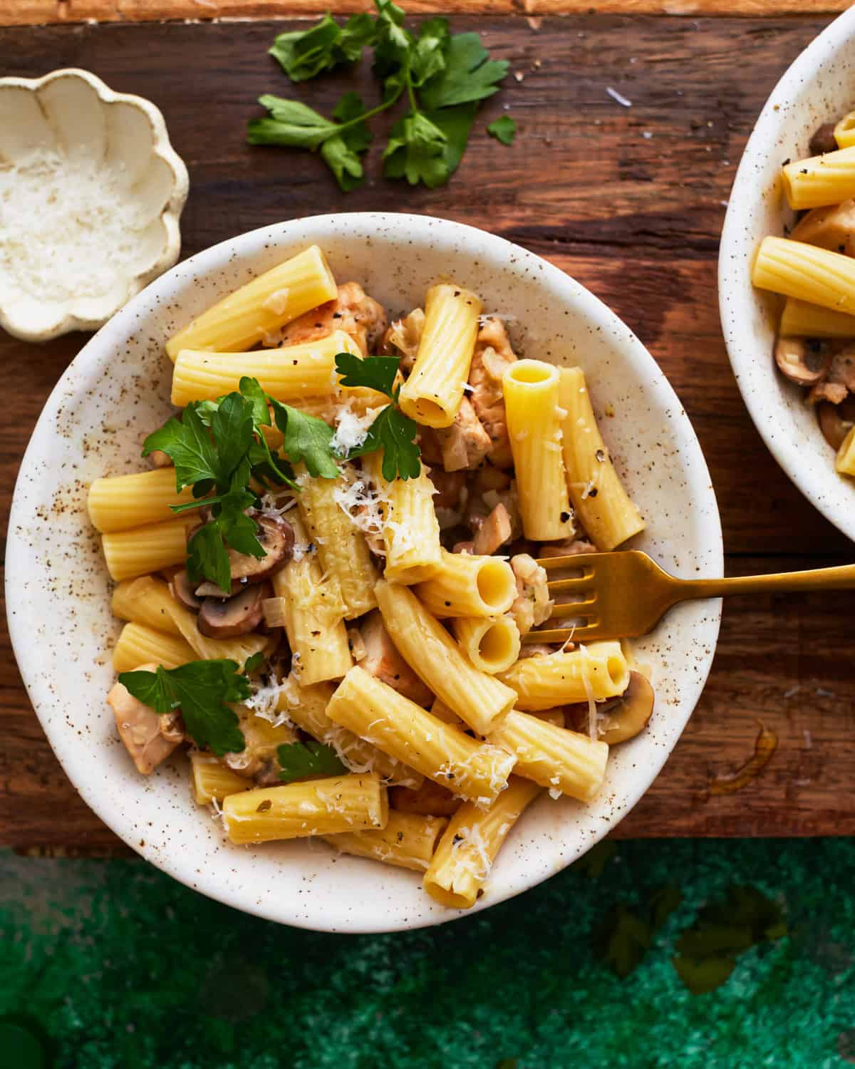 overhead view of a serving of chicken mushroom pasta in a white bowl with a fork.