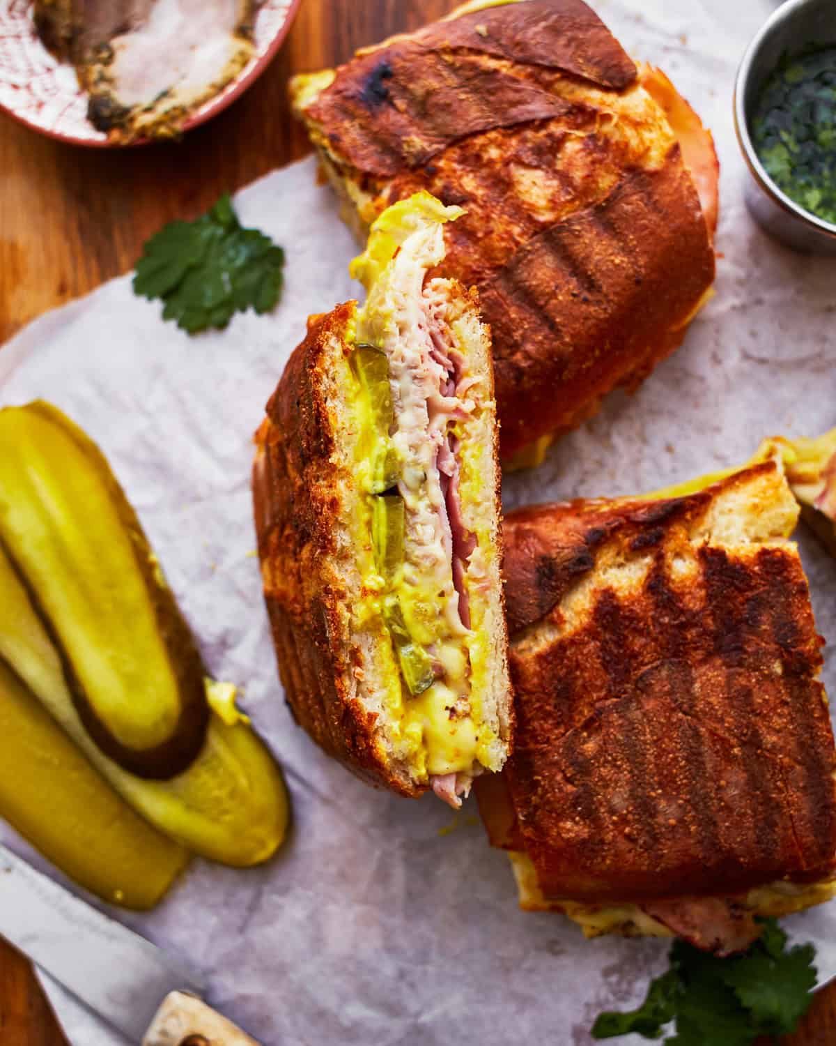 upturned half of a cuban sandwich leaning against the other half to show the filling.