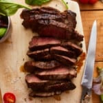 overhead view of sliced ribeye steak on a cutting board.