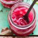 overhead view of a rubber spatula in a jar of pickled red onions.