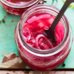 overhead view of a rubber spatula in a jar of pickled red onions.