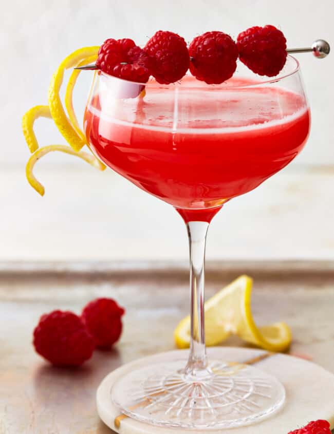 A raspberry lemon drop martini cocktail, garnished with raspberries and lemon.
