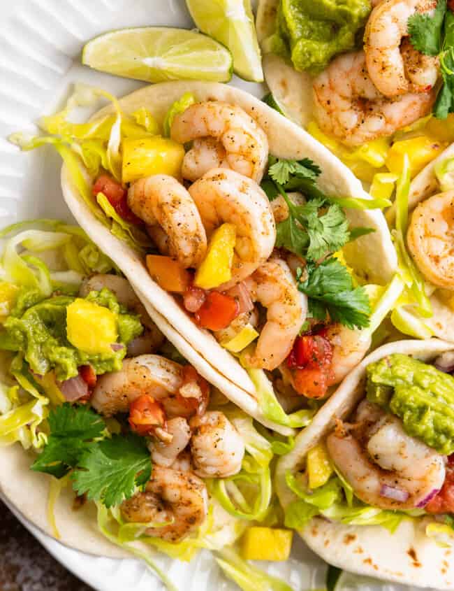 A plate of shrimp tacos with pineapple slaw and guacamole.