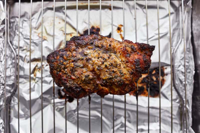 cooked pork shoulder on a wire rack set in a foil-lined baking sheet.