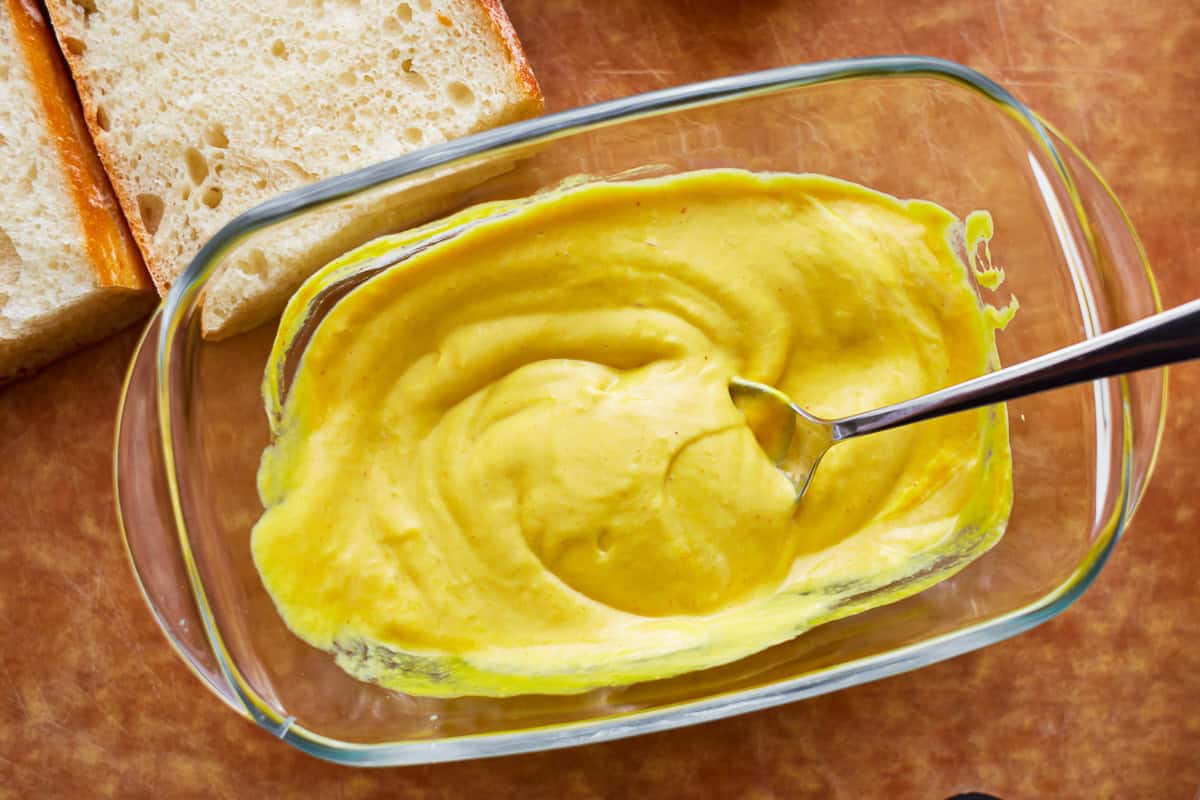 mayo-mustard sauce in a glass dish with a spoon.