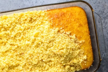 a baked lemon cake in a glass baking dish, partially torn into crumbs.