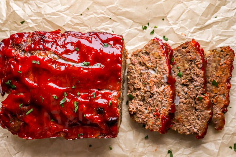 overhead view of a partially sliced meatloaf on parchment paper.