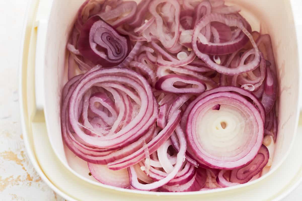 blanched sliced red onions in a white bowl.
