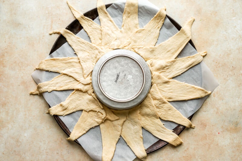 crescent roll triangles arranged around a bowl on a baking sheet.