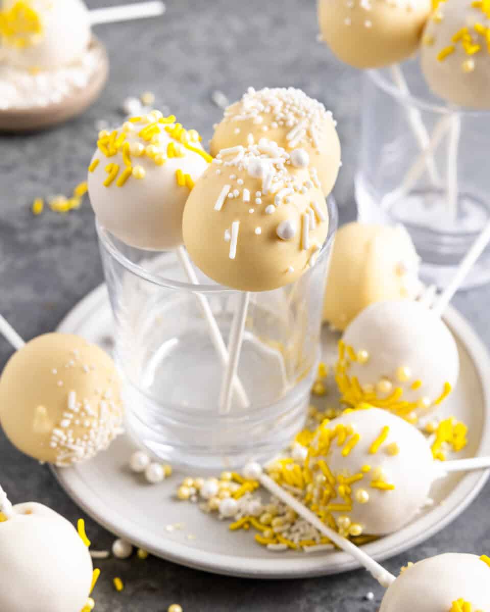 A collection of lemon cake pops arranged in glasses and on a plate.