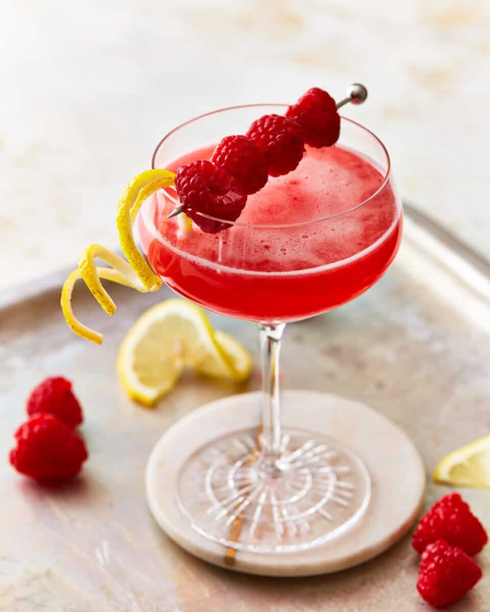 A raspberry lemon drop martini garnished with fresh berries and lemon.
