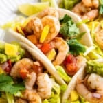 A plate of shrimp tacos with pineapple and cabbage slaw.