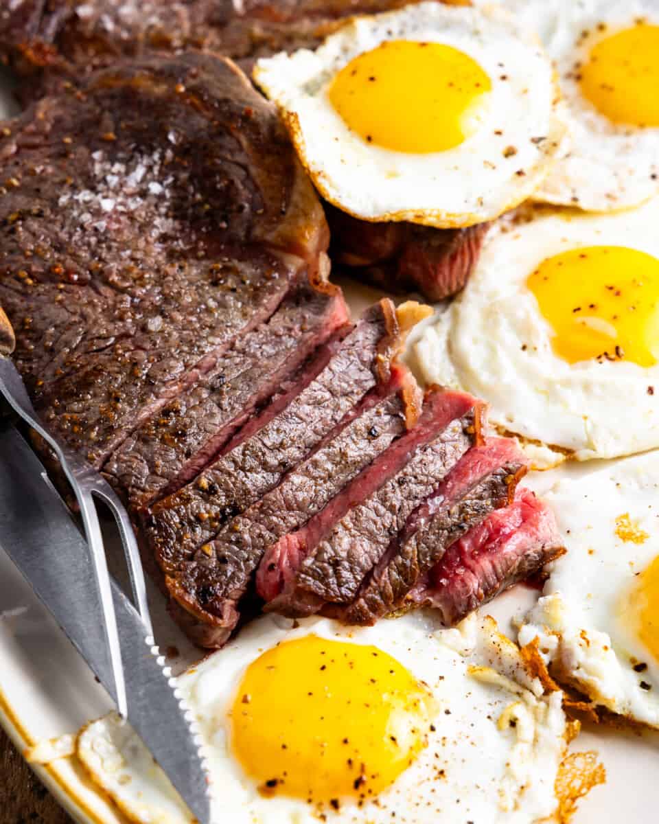close up on a platter of steak and fried eggs.
