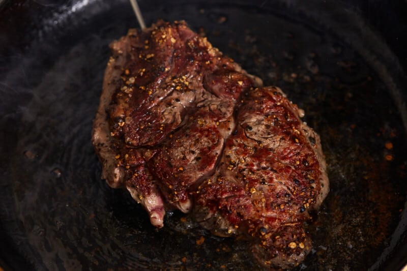 seared ribeye steak in a cast iron pan.
