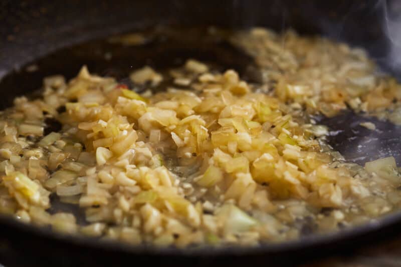 diced onions and garlic cooking in a pan.