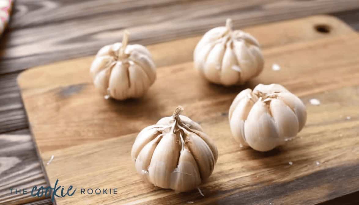 4 bulbs of garlic on a cutting board.