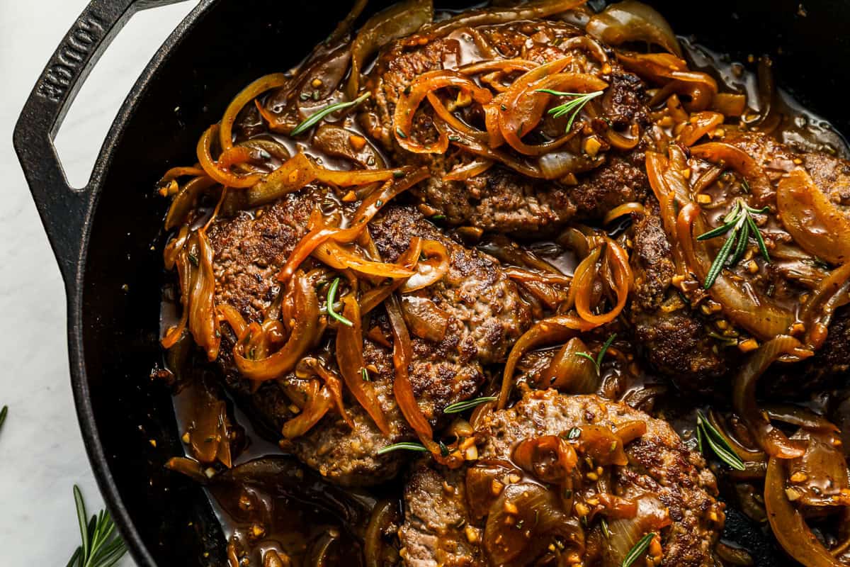 close up view of cube steaks in gravy in a pan.