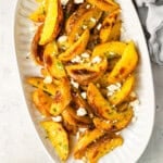 overhead view of greek potatoes topped with feta on a serving platter.