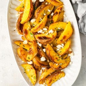 overhead view of greek potatoes topped with feta on a serving platter.