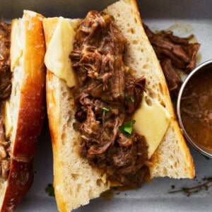 a hot beef sandwich on a split roll with cheese.