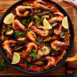 overhead view of paella garnished with lemon wedges.