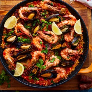 overhead view of paella garnished with lemon wedges.