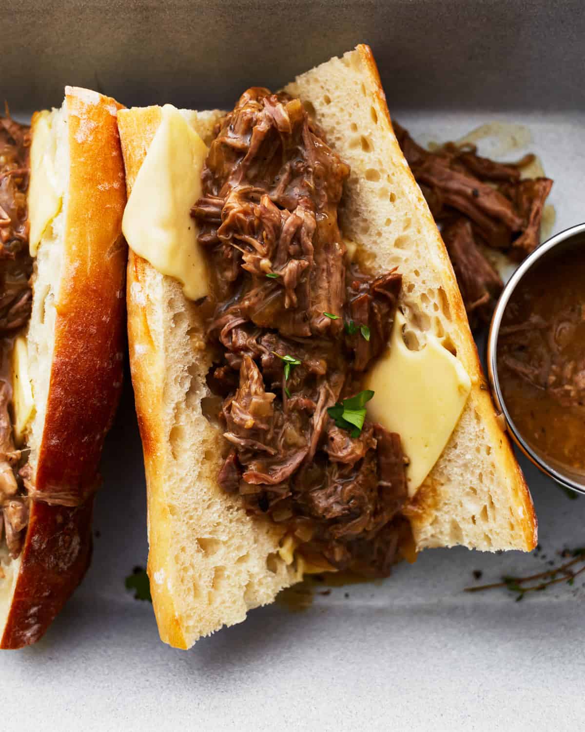a hot beef sandwich on a split roll with cheese.