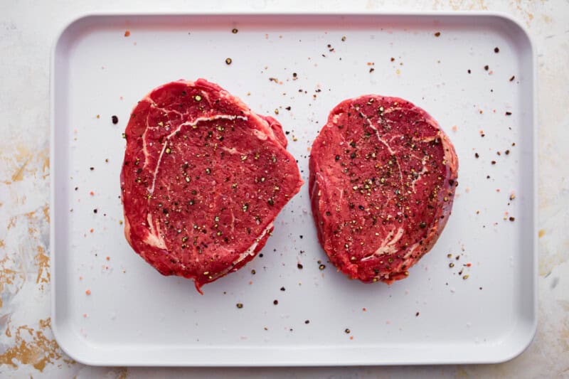 2 pieces of seasoned beef on a baking sheet.