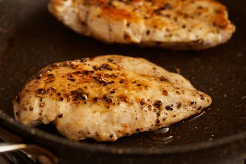 chicken breasts cooking in a pan.