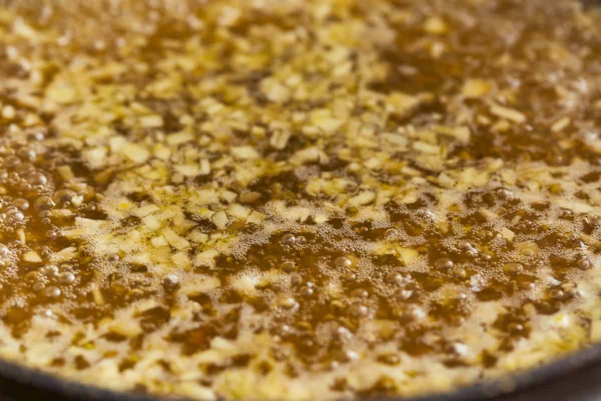 chicken broth and garlic simmering in a pan.