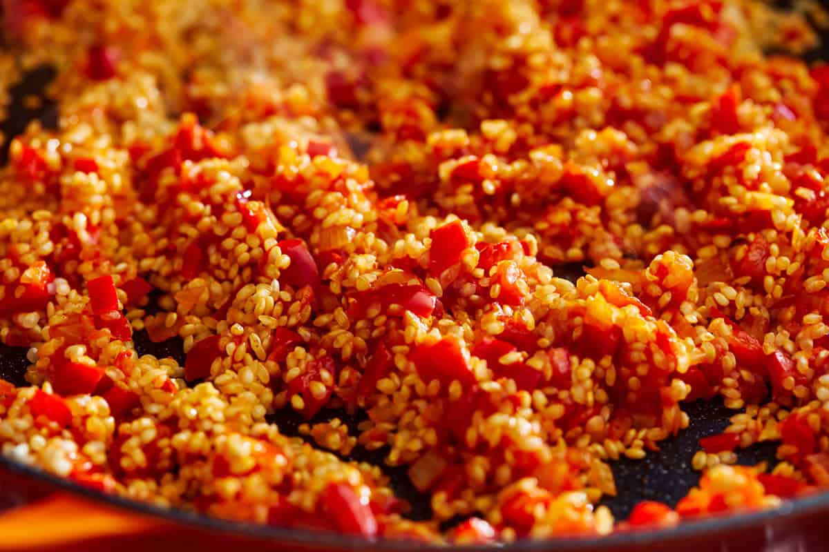 rice and sofrito tossed together in a pan.