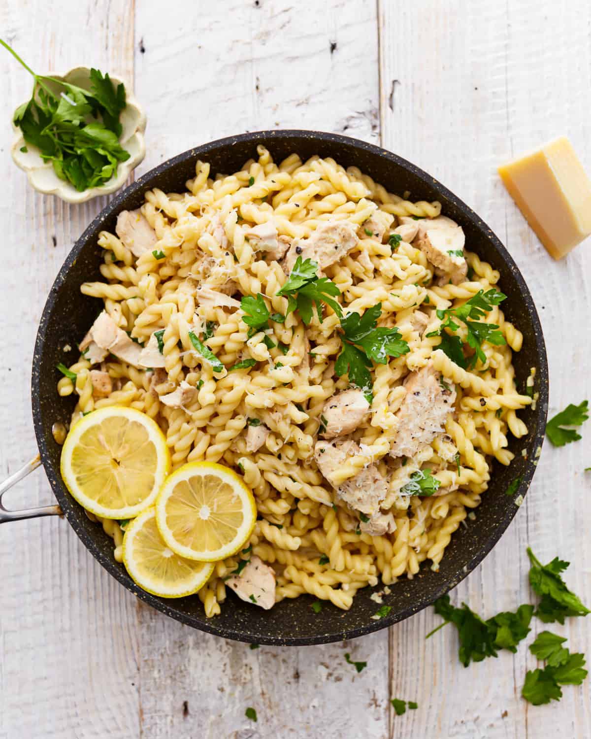overhead view of lemon chicken pasta in a pan with lemon slices.