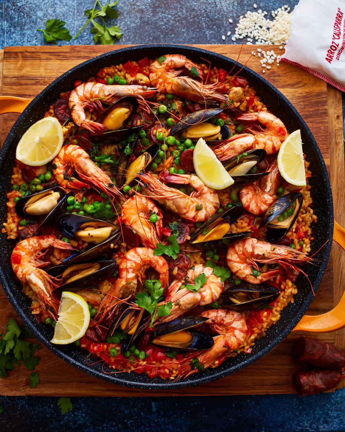 overhead view of paella garnished with lemon wedges.