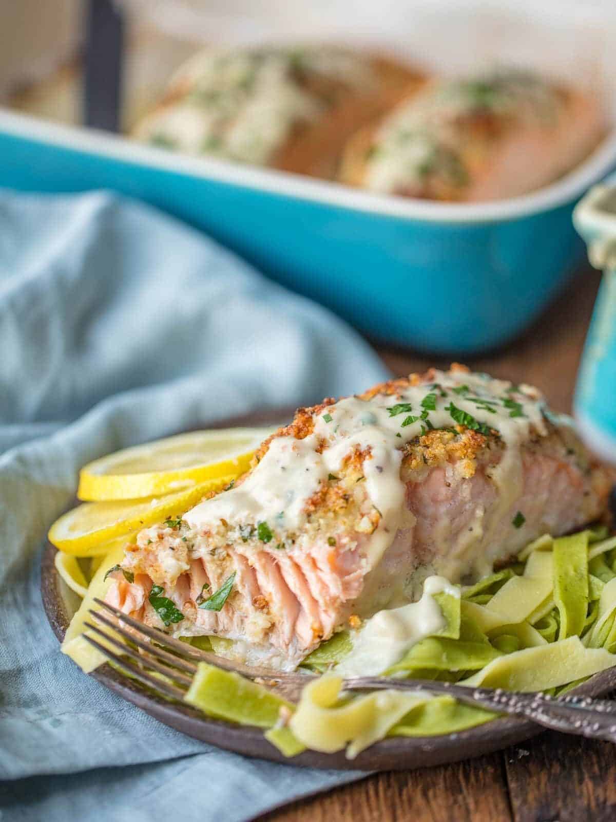 A plate of baked salmon with the baking dish in the background