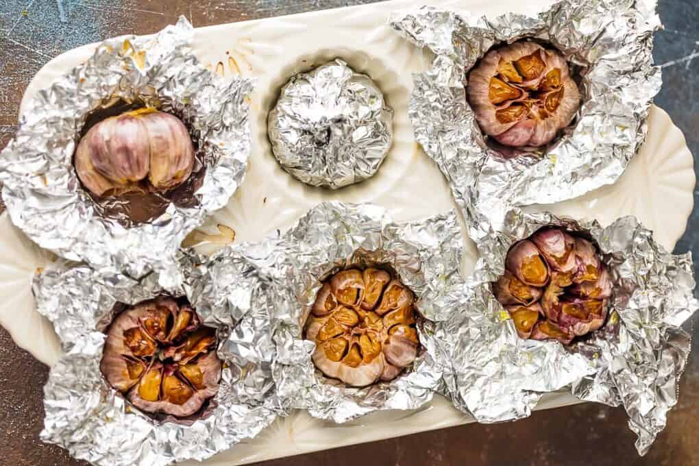 garlic covered in foil in cupcake baking dish