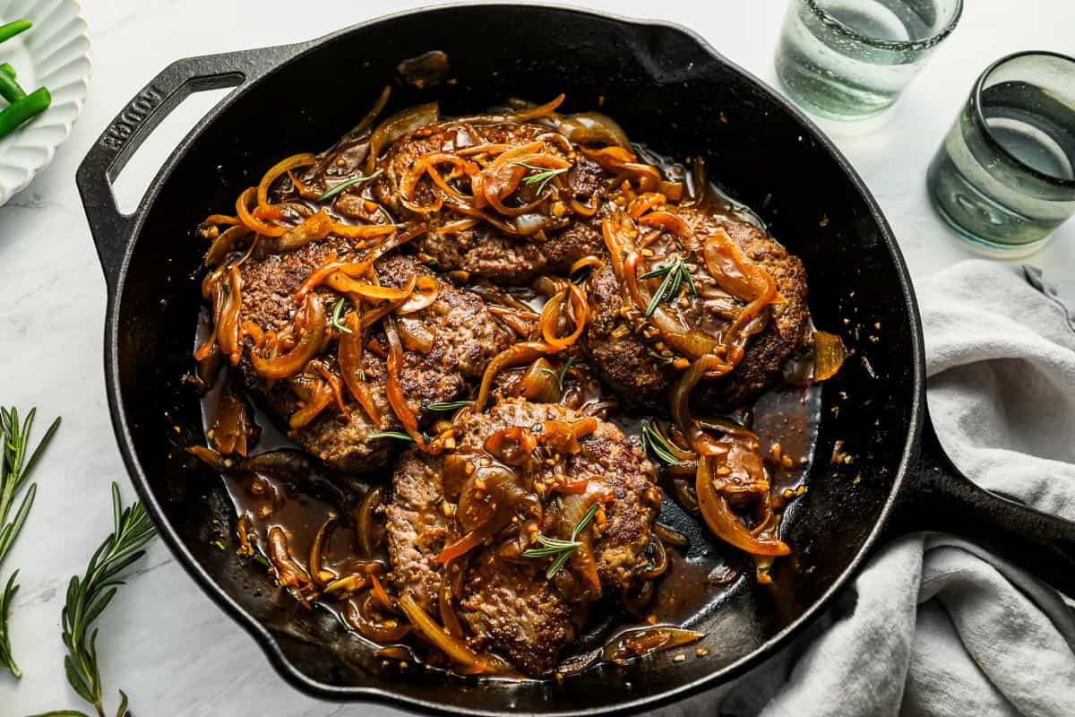 cube steaks in a pan with onion gravy.