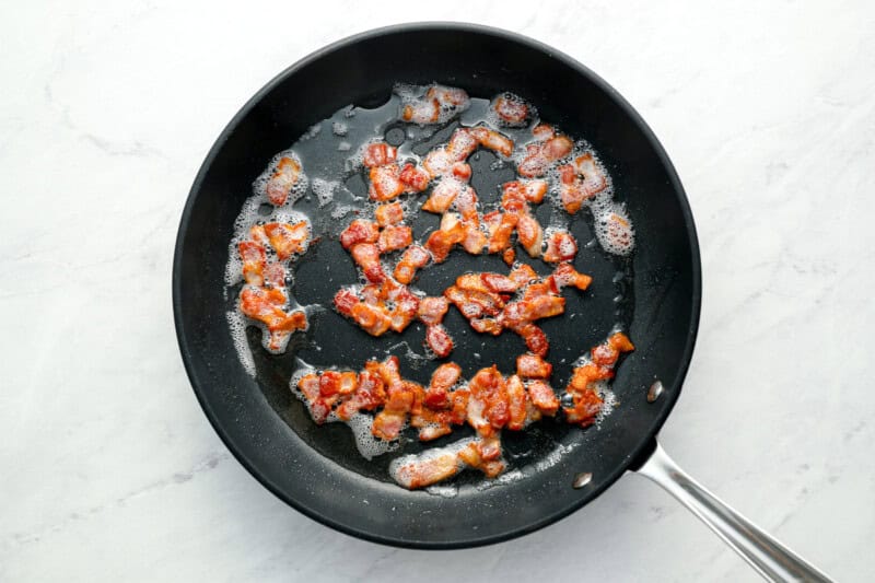 chopped bacon cooking in a pan.