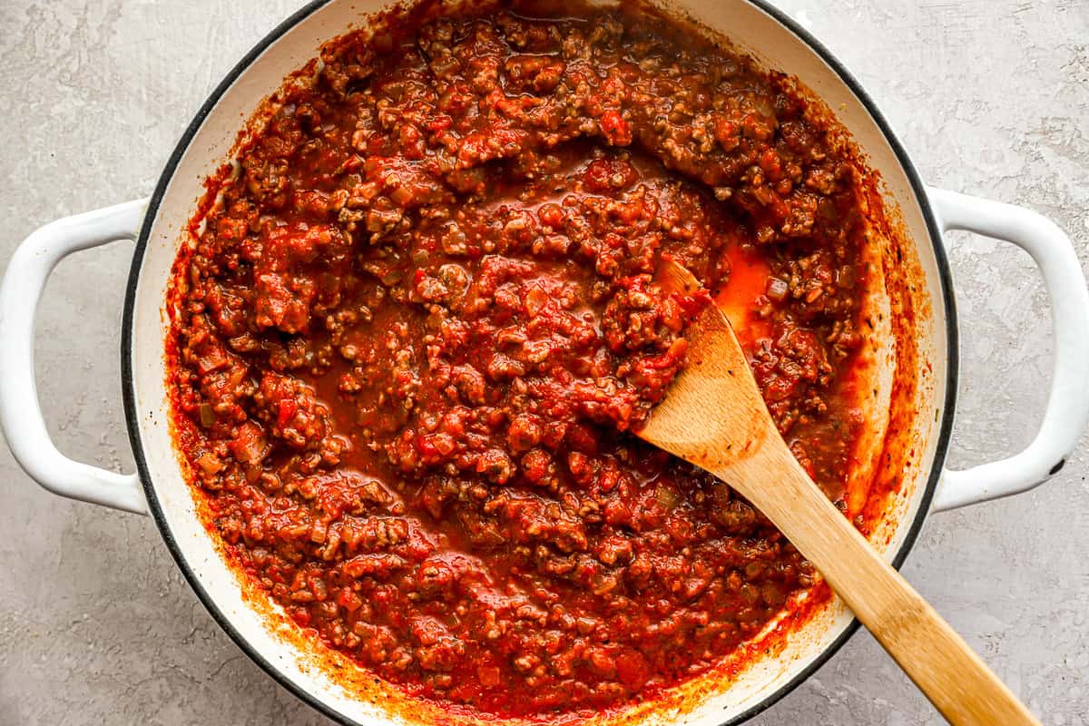 tomato meat sauce in a pot with a wooden spoon.