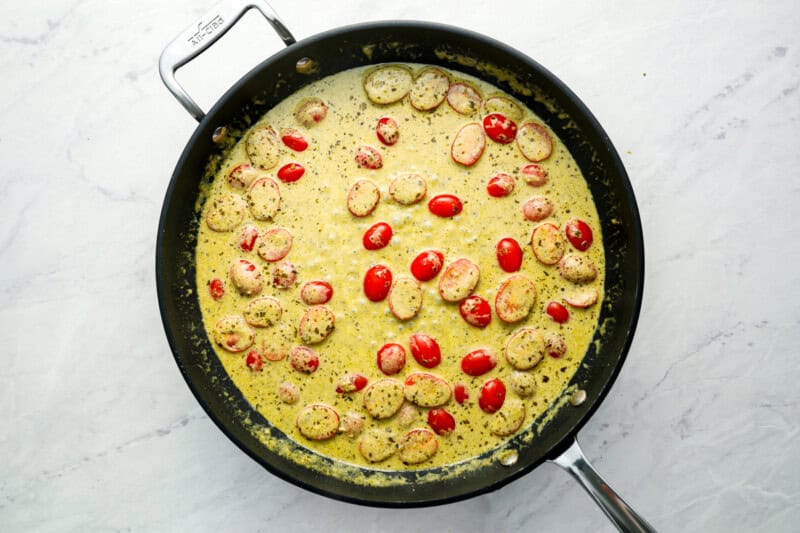 creamy pesto sauce and tomatoes in a skillet.
