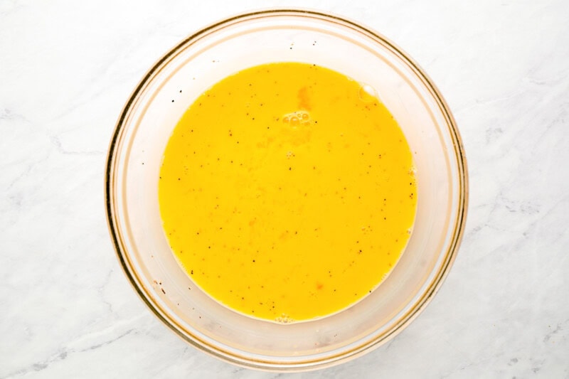 seasoned eggs whisked in a glass bowl.