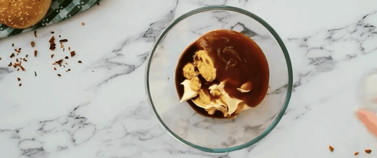 Combining the ingredients for burger sauce in a glass bowl.
