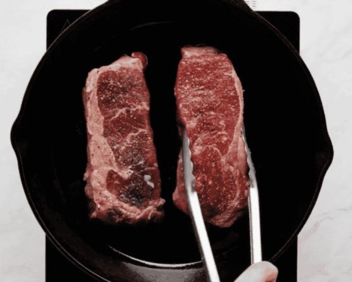 Searing two rib eye steaks in a cast iron pan. - 10